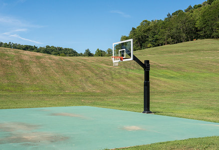 挡板摄影照片_带篮球或无挡板篮球网的外部运动场，周围环绕着田野
