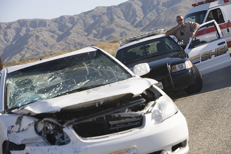 警察在沙漠公路上一辆损坏的汽车前使用无线电