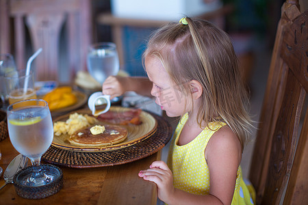 在度假村餐厅吃早餐的可爱小女孩