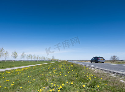 荷兰语摄影照片_荷兰弗莱福兰省蓝天下开放的春天景观，道路和汽车