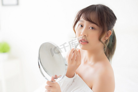 口红u盘摄影照片_美丽的肖像年轻亚洲女人看着镜子应用 mak