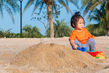 开朗的女儿女孩有趣地挖沙子玩玩具