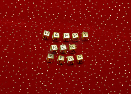 带有亮片的红色天鹅绒上珠子的短语“新年快乐”