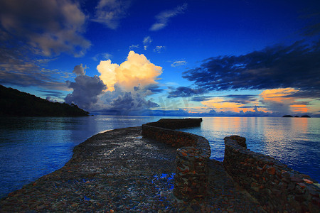 蓝色大海摄影照片_在美丽的晨光天空下，进入蓝色大海的岩石桥