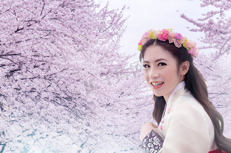 穿着樱花背景的传统韩国韩服的亚洲女性。