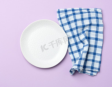 空圆的白色陶瓷盘子和蓝色餐巾，紫色酒泉