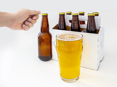一个人打开 Pilsner Style Lager 棕色瓶装啤酒和一品脱啤酒