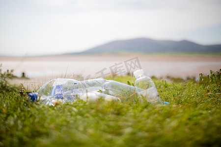 草地上的几个空塑料瓶，背景是一座山