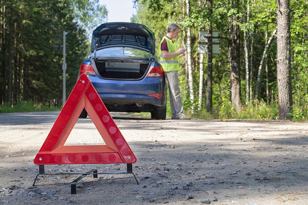 靠近汽车的乡村道路一侧的便携式警示三角标志