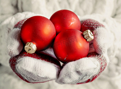 双手戴着手套，拿着红色的复古圣诞球特写
