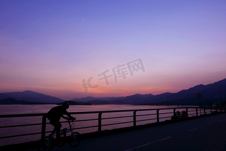 自行车、栅栏、山、渐变紫色天空的剪影