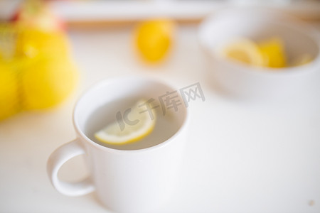 柠檬杯子摄影照片_一杯柠檬茶放在一张被柠檬包围的白桌上