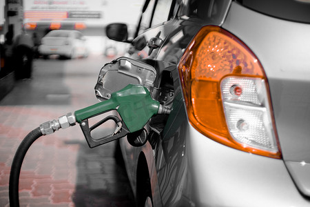 石油价格摄影照片_汽油泵加油站的人将喷嘴插入汽车油箱，并在自动切断石油柴油泵中启动燃油泵