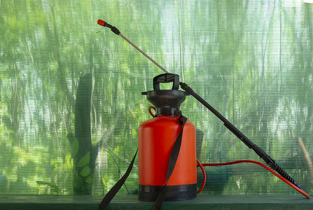 花洒摄影照片_绿色背景中的橙色花园农药喷雾器