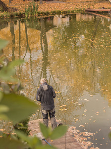 一名男性社会工作者生态学家站在河岸上观察城市池塘的水况。