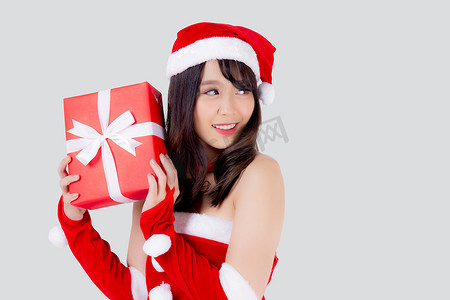 美丽的肖像年轻亚洲女人快乐地拿着红色礼品盒，在圣诞节假期中兴奋地与白色背景隔离，亚洲女孩惊喜并在节日的圣诞节和新年庆祝。
