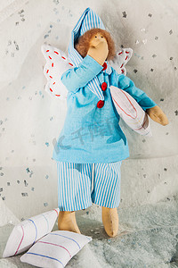 蓝色的枕头摄影照片_穿着蓝色睡衣和枕头的柔软纺织娃娃