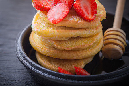 堆栈的甜薄煎饼用草莓和蜂蜜。