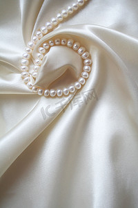 闪闪发光摄影照片_以珍珠作为婚礼背景的光滑优雅的白色丝绸
