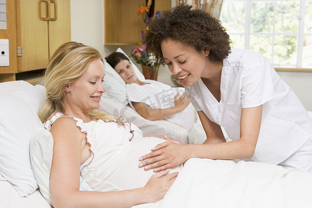 护士检查孕妇的腹部并微笑