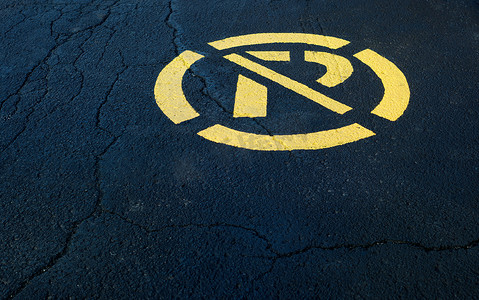 涂沥青摄影照片_黑色沥青上没有涂成黄色的停车标志