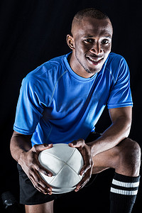 男人跪着摄影照片_跪着带球微笑的橄榄球运动员肖像