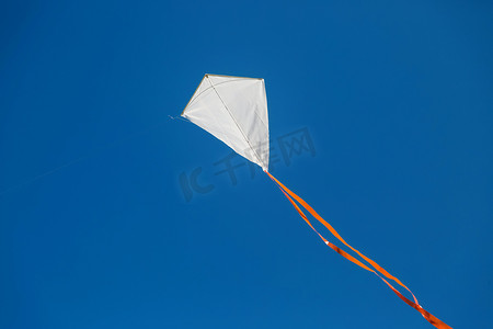 白色的红尾风筝在蔚蓝晴朗的天空中飞翔