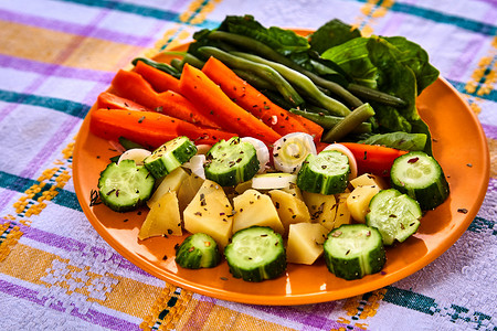 一勺蒸熟的新鲜蔬菜，包括切碎的胡萝卜、豌豆和土豆条