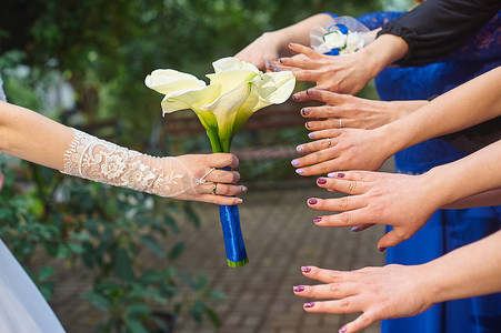 婚礼邀请函装饰摄影照片_伴娘的手被马蹄莲的婚礼花束吸引