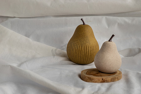 白色织物背景上的两个陶瓷梨果实。