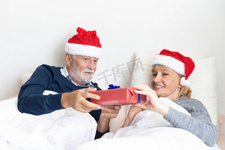 圣诞节期间，老年夫妇在床上交换礼物