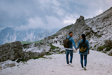 一对夫妇在雾蒙蒙的天气里在意大利多洛米蒂山徒步旅行，可以欣赏到意大利多洛米蒂山 Tre Cime 峰的壮丽景色