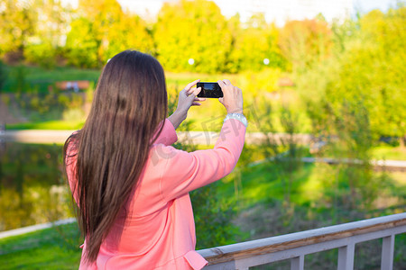 年轻女人在秋日用手机拍照