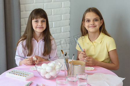 孩子们坐在家里的桌子旁准备画复活节彩蛋。