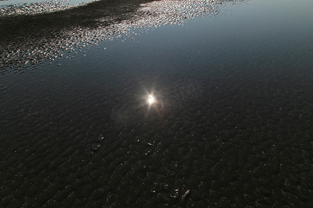 当水落下时，太阳在海中海滩的水中反射