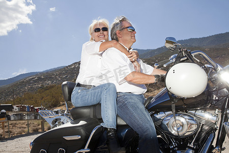 在乡村风景中一起骑摩托车的老年夫妇