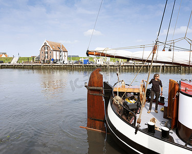 女人在荷兰特塞尔岛奥德柴尔德港驾驶旧木帆船，人们捕蟹，男人拍照
