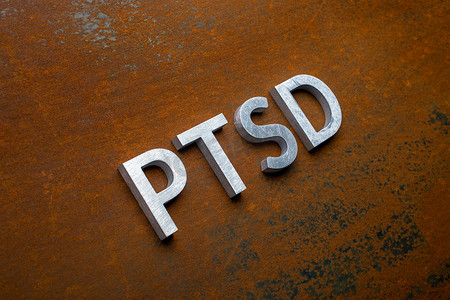 扁平风美妆摄影照片_PTSD 一词以倾斜的对角线视角放置在扁平生锈钢板背景上的银色金属字母