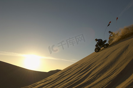 日落时在沙漠中骑四轮摩托的男子
