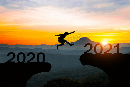 2020 年和 2021 年新年概念之间的人跳剪影。