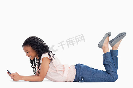 一名躺在地上的年轻女子正在用她的手机发短信