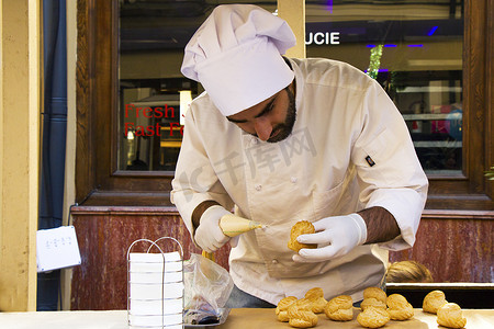 糕点场景摄影照片_糖果厨师烹饪甜点场景，厨师装饰蛋糕，并在城市节的第比利斯街头工作。