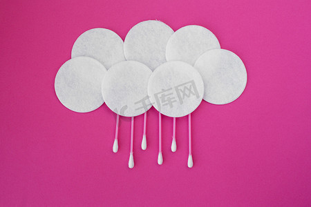 粉红色棉芽的顶视图，白色头和白色圆形棉盘铺在云中，粉红色背景上有雨滴
