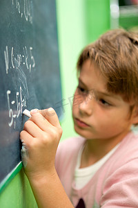 黑板写字摄影照片_年轻学生在黑板上写字的特写