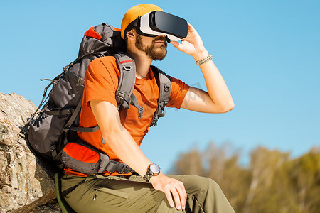游戏娱乐摄影照片_成功的年轻人，使用虚拟现实护目镜在山区旅游，在夏天度假