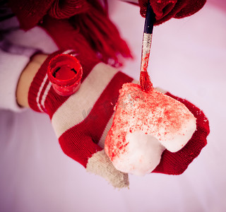 雪心摄影照片_红手套把雪心画成红色。