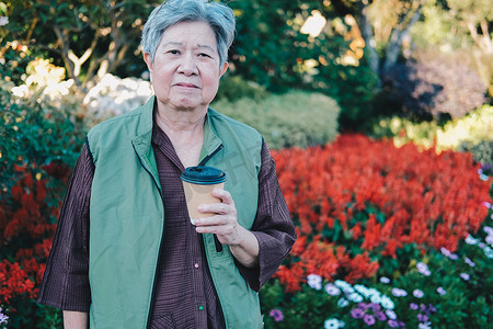 咖啡茶摄影照片_亚洲老年老年妇女在花园里喝咖啡茶。