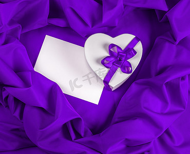 爱心贺卡摄影照片_紫色布料上有心形的爱心贺卡