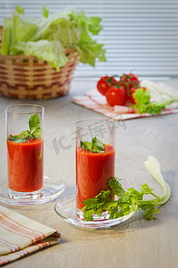 桌上放着两杯西红柿汁、西红柿、茎和芹菜叶