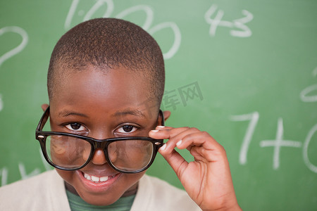 捐款公示霜手势摄影照片_微笑的男小学生看着他的眼镜